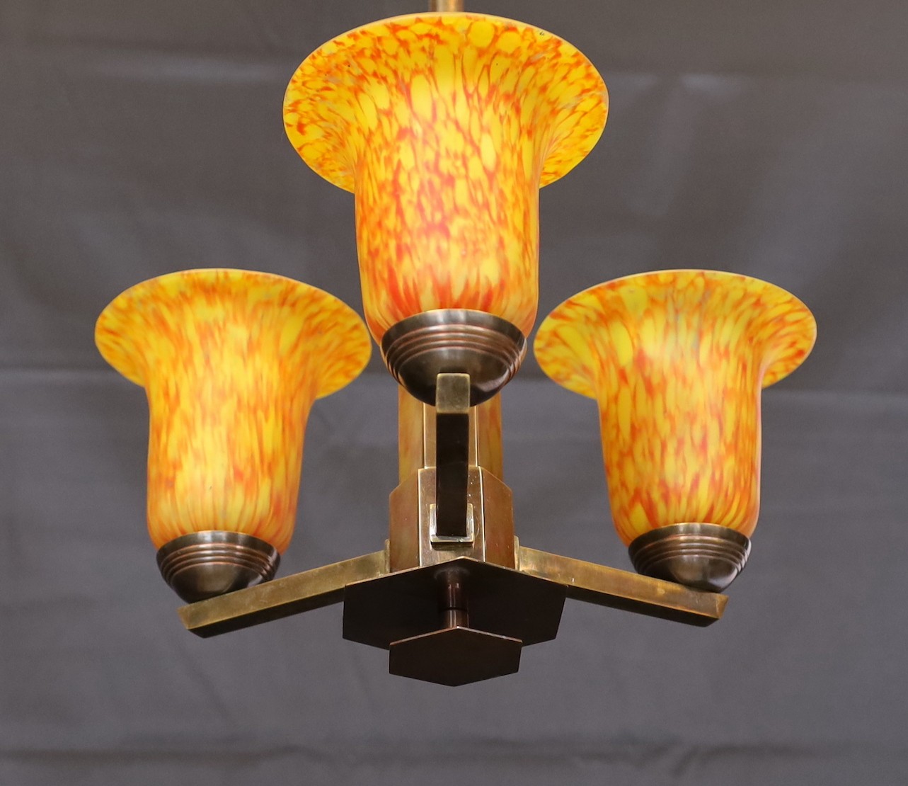 A 1930s GLC bronzed metal light fitting with three marbled amber glass shades, height 60cm. width 33cm